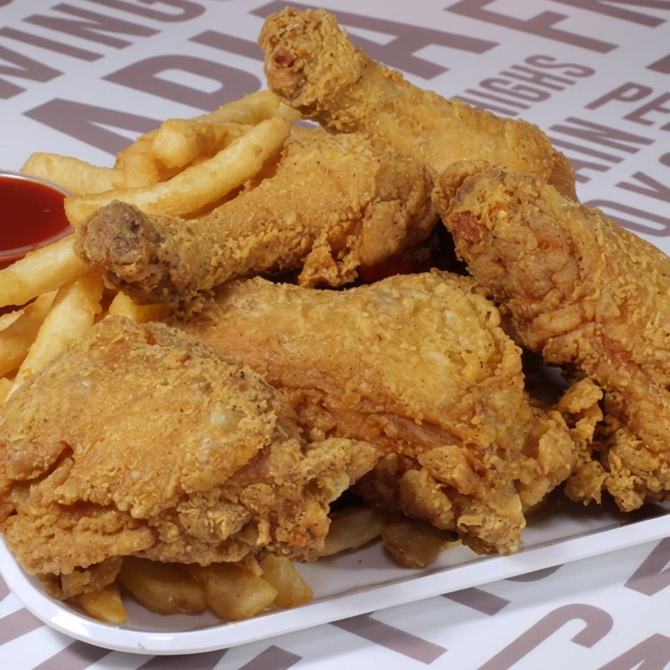 Crispy fried chicken pieces and fries with red dipping sauce on a platter at Captain Hooks Fish and Chicken.