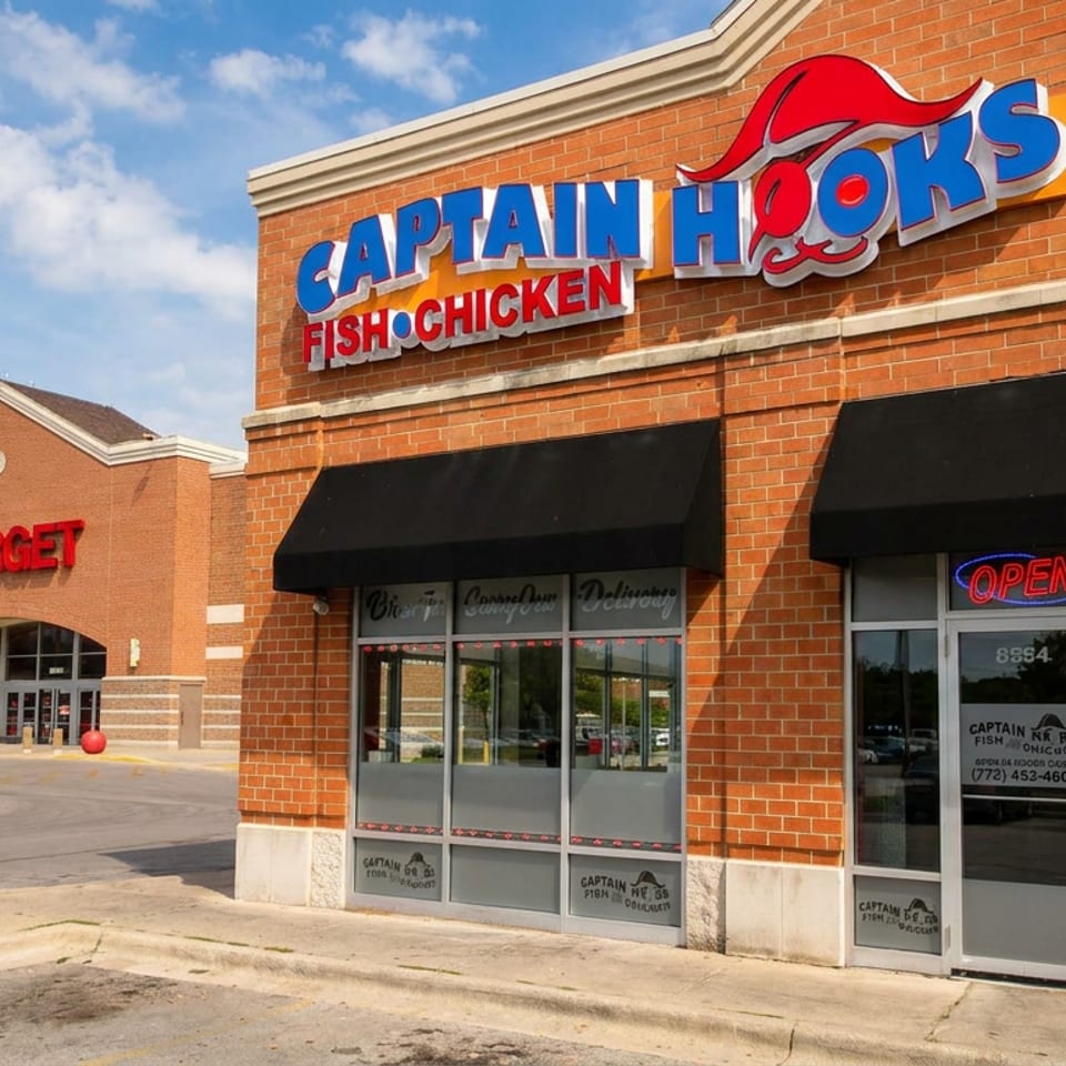Captain Hooks Fish Chicken restaurant storefront with open sign beside a Target store in a brick shopping center.